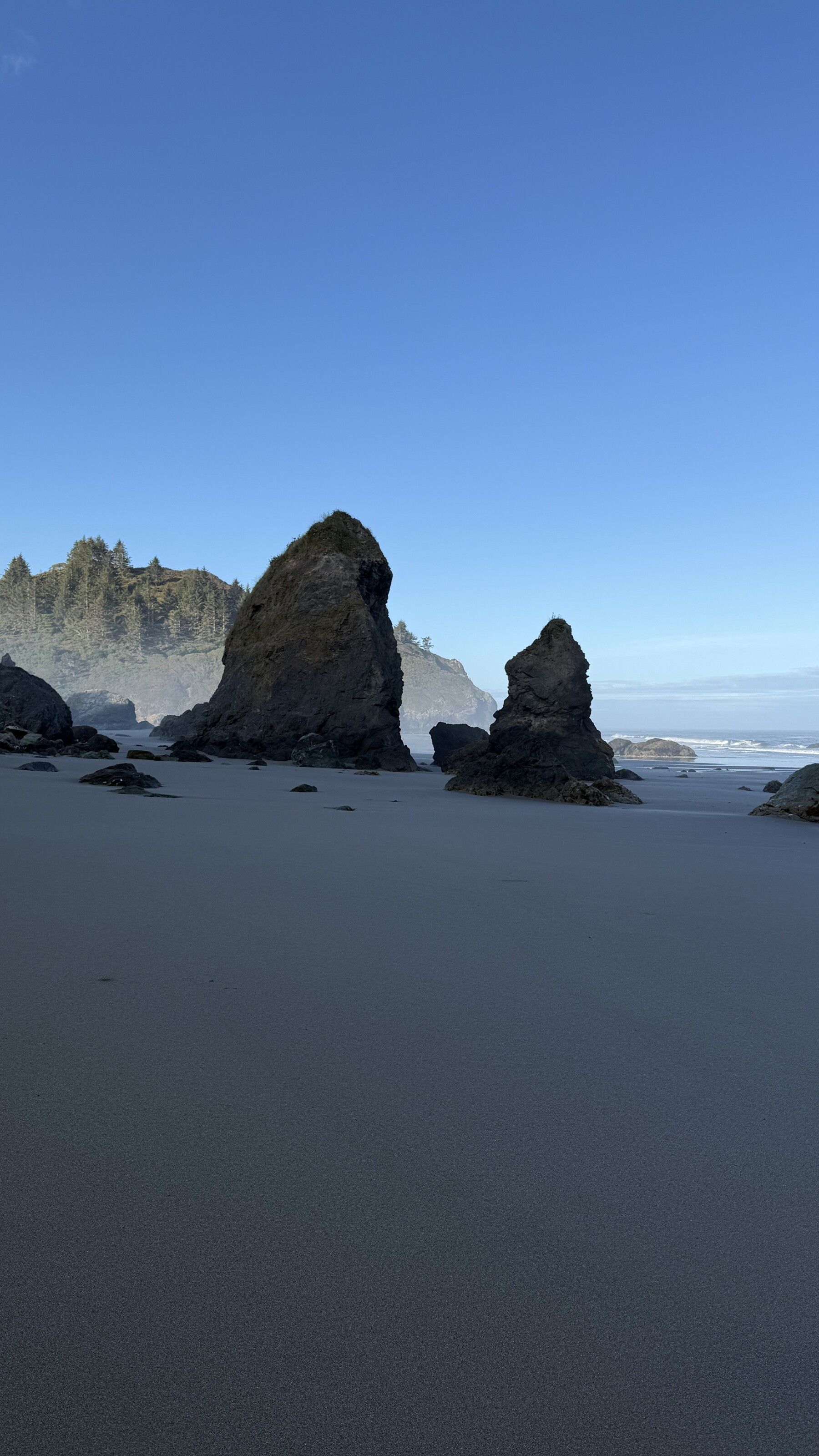 Sea stacks rising from a sandy Trinidad beach under a clear blue morning sky